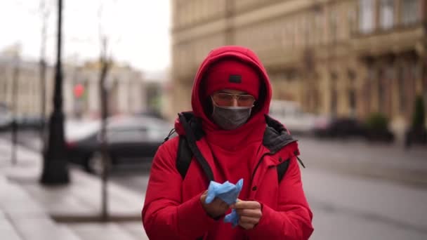 Un hombre de rojo lleva guantes protectores en una calle de la ciudad — Vídeos de Stock