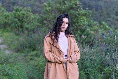 Model kadın zarif kıyafetler giyerek doğada poz veriyor.