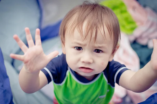 Bir erkek bebek kucağına alınmak istediğini söylüyor. Görüntü editoryal ya da ticari olarak kullanılabilir.