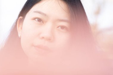 Çekici bir Asyalı kadının kameraya bakışının yumuşak odak arkaplanı. Görüntü editoryal ya da ticari olarak kullanılabilir.