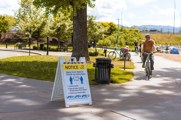 Kelowna, BC / Kanada - 18 Mayıs 2020: Covid-19 Salgınında Sosyal Mesafeyi Koruyun Bisikletçi Gezintileri ve Vatandaşlar Parkın Keyfini Çıkarırken.