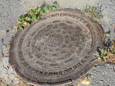 Asfalt caddesindeki eski lağım çukuru. Rögar kapağı, eski metal kanalizasyon kapağı.