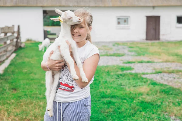彼女の腕の中にかわいいヤギを持つ少女の肖像画 — ストック写真