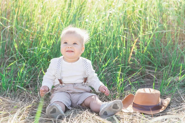 Piękne Blond Dziecko Garniturze Szelkami Siedzi Trawie Pobliżu Kapelusza — Zdjęcie stockowe