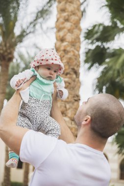 Baba, sevimli çocuğu bahçede tutuyor.