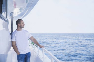 Bir yatta çekici bir adam denizdeki mesafeye bakar