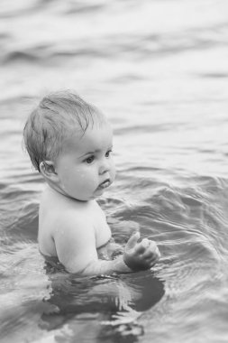 Nehirde siyah beyaz yüzen güzel sarışın bebek.