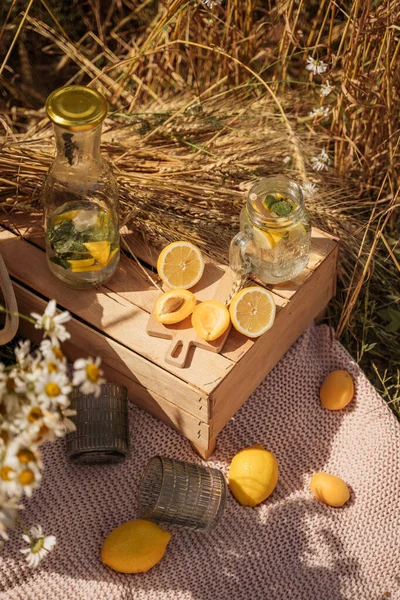 picnic in the wheat field. lemons, apricots, a wooden table on a blanket. lemonade in glasses. aesthetics of breakfast in nature. outdoor recreation. no people