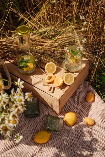 picnic in the wheat field. lemons, apricots, a wooden table on a blanket. lemonade in glasses. aesthetics of breakfast in nature. outdoor recreation. no people