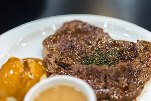 Meat steak (Beef or Pork steak) with mashed potatoes in white dish for sale at Thai street food market or restaurant in Bangkok Thailand