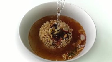 Ağır çekim Pour sıcak suyun içine bir anlık erişte beyaz kase ve fastfood ve sağlıksız yiyecek ya da şişman kavramı olduğunu