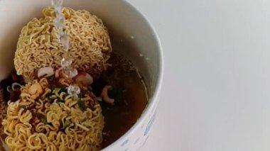 Ağır çekim Pour sıcak suyun içine bir anlık erişte beyaz kase ve fastfood ve sağlıksız yiyecek ya da şişman kavramı olduğunu