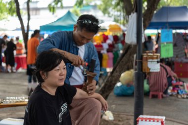 Bangkok, Tayland - 28 Temmuz 2017: hizmet Tay Masaj tedavi ağrı ve sancıları için tahta çekiç almaya kimliği belirsiz kadın Tay. Hizmetin açık bahçede geliyor.