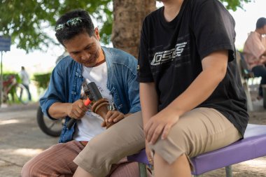 Bangkok, Tayland - 28 Temmuz 2017: hizmet Tay Masaj tedavi ağrı ve sancıları için tahta çekiç almaya kimliği belirsiz kadın Tay. Hizmetin açık bahçede geliyor.