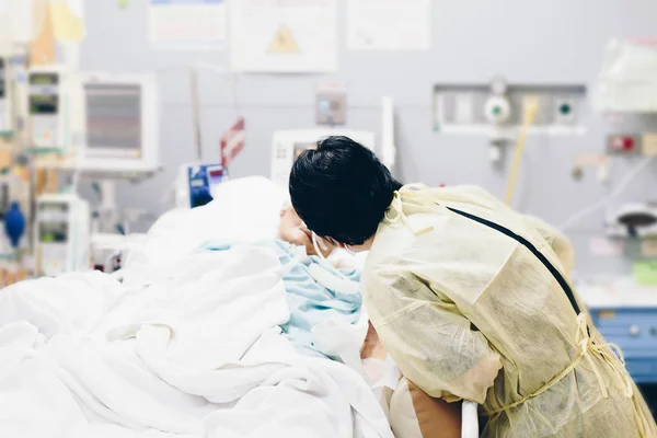 Asian women 40s years old is a patient relative taking care of the CRE. or VRE. infected elder patient 80s years old on patient bed in intensive care unit (ICU.) room at hospital.