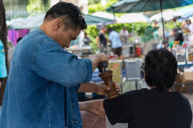 Bangkok, Tayland - 28 Temmuz 2017: hizmet Tay Masaj tedavi ağrı ve sancıları için tahta çekiç almaya kimliği belirsiz kadın Tay. Hizmetin açık bahçede geliyor.