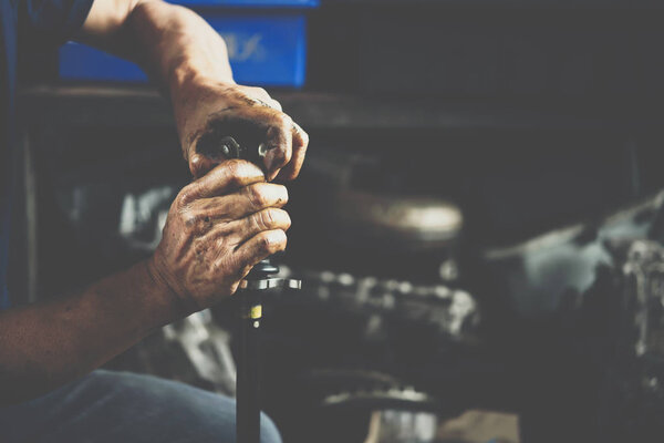 Car mechanic or serviceman disassembly and checking a car alloy chrome wheel for fix and repair suspension problem at car garage or repair shop