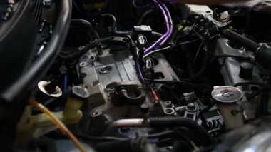 Araba tamircisi veya servis elemanı, araba garajında veya tamirhanesinde tamir ve onarım sorunu için bir araba motoru (Buji değiştirme) kontrol