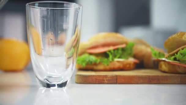 Het Gieten Van Verse Sinaasappelsap Water Glas Met Wazig Croissant — Stockvideo