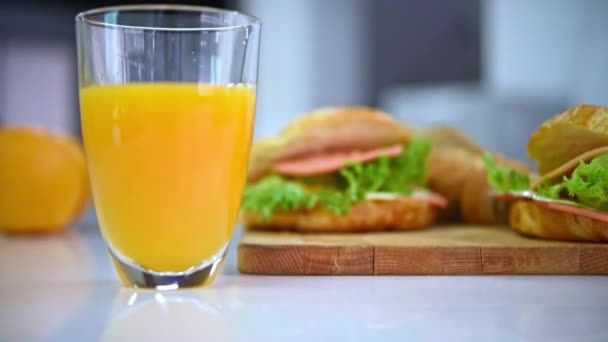 Despejando Água Suco Laranja Fresca Vidro Com Sanduíche Presunto Croissant — Vídeo de Stock