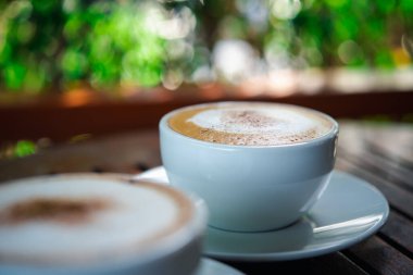 Kafe veya restoranda müşterilere servis yapmak için ahşap masadaki beyaz kahve fincanındaki kahve içeceği.