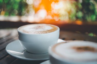 Kafe veya restoranda müşterilere servis yapmak için ahşap masadaki beyaz kahve fincanındaki kahve içeceği.