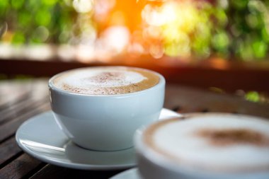 Kafe veya restoranda müşterilere servis yapmak için ahşap masadaki beyaz kahve fincanındaki kahve içeceği.