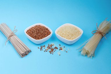 Kurutulmuş karabuğday sobalı erişte, pirinç eriştesi ve karabuğday dilimleri, mavi arka planda pirinç. Sağlıklı konsept, glütensiz.