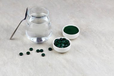 Klorella ya da arka planda bardakta su olan spirulina. Süper yiyecek ve detoks kavramı.