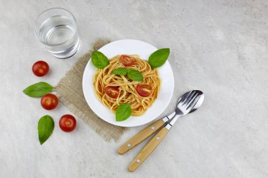 Baharatlı domates soslu İtalyan makarnası domates ve açık arkaplanda fesleğen..