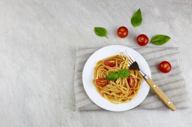 Baharatlı domates soslu İtalyan makarnası domates ve açık arkaplanda fesleğen..