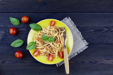 Klasik İtalyan Bolonez makarnası, domatesli ve fesleğenli, koyu ahşap arka planda..