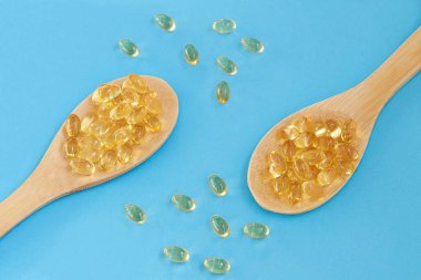 Mavi arka planda tahta kaşıklarda balık yağı