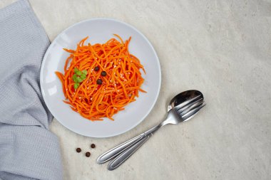 Hafif arka planda bir tabakta baharatlı havuç turşusu, baharatlı Kore aperatifi. Vejetaryen sağlıklı yemek.