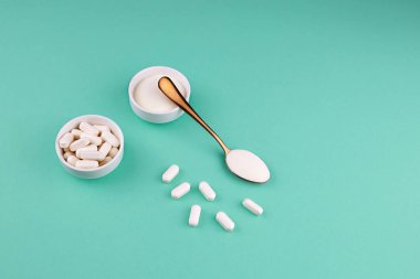 Yeşil arka planda kolajen protein tozu ve kolajen hapları. Cilt, kemik ve eklemler için doğal güzellik ve sağlık desteği.