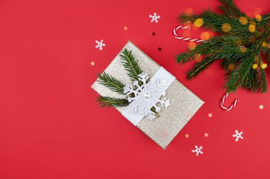 Noel kompozisyonu. Hediye, kırmızı Noel süsleri, köknar dalları ve kırmızı arka planda ışıklar. Düz konum, üst görünüm, kopyalama alanı