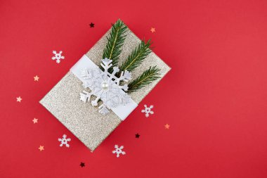 Noel kompozisyonu. Hediye, kırmızı Noel süsleri, kırmızı arka planda köknar dalları. Düz konum, üst görünüm, kopyalama alanı