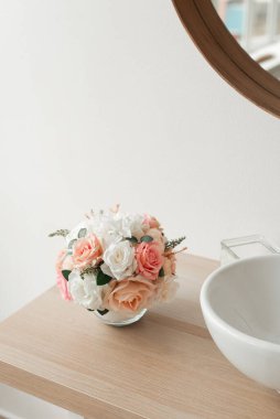 Banyo içinde yapay çiçekler var. Yuvarlak vazoda dekoratif çiçekler. Yuvarlak vazodaki yapay çiçekler. Banyo içi beyaz. Dekoratif çiçekler. 