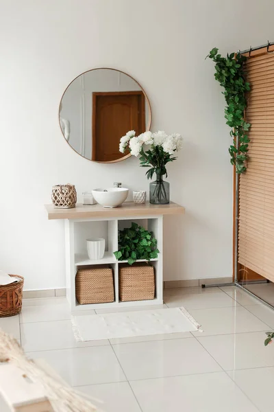 Banyo içinde yapay çiçekler var. Banyoda dekoratif çiçekler var. Vazodaki yapay çiçekler. Banyo içi beyaz. Dekoratif çiçekler. 