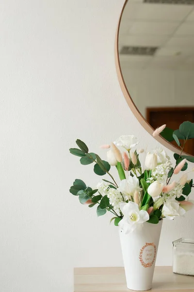 Artificial flowers in the bathroom interior. Decorative flowers in the bathroom. Artificial flowers in a vase. White bathroom interior. Decorative flowers.
