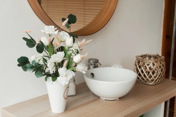 Banyo içinde yapay çiçekler var. Banyoda dekoratif çiçekler var. Vazodaki yapay çiçekler. Banyo içi beyaz. Dekoratif çiçekler. 