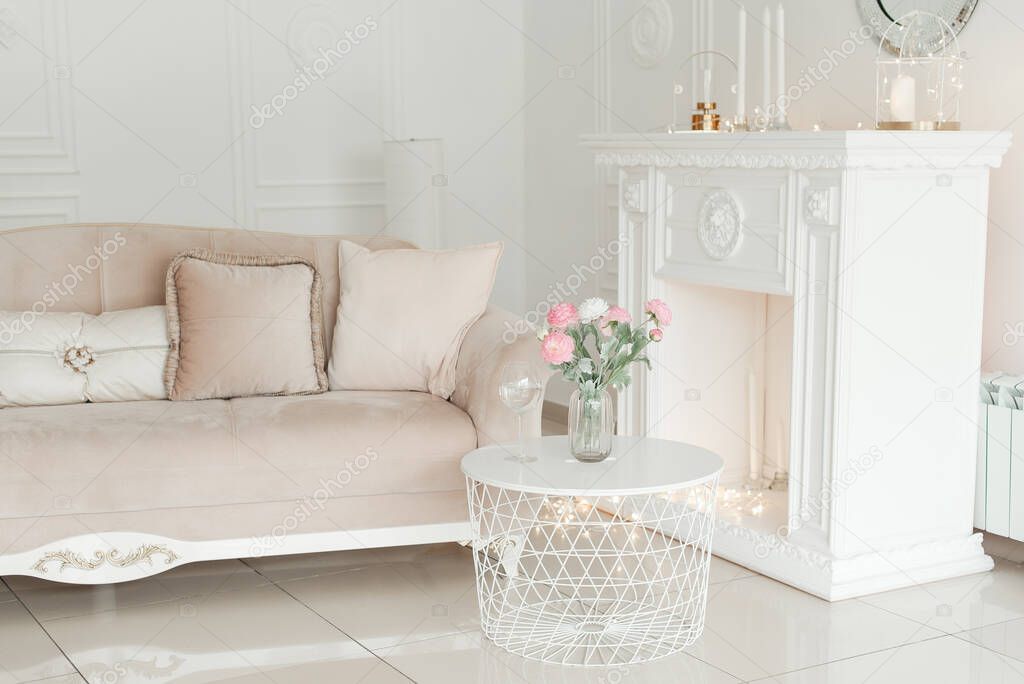 Artificial flowers in the interior. Decorative flowers in the interior. Artificial flowers in a vase. White interior of the room. Decorative fireplace. 
