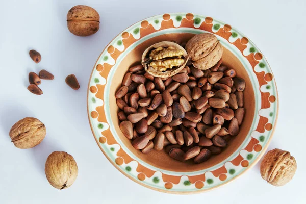 walnuts and pine nuts on a white background lie in a beautiful plate.
