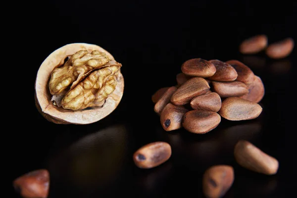walnuts and pine nuts on a black background