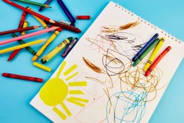 renkli kalemler ve mavi bir arka plan üzerinde çocuk çizimleri