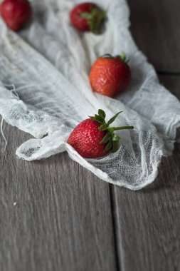 Tek bir böğürtlen, beyaz kumaşta yeşil kuyruklu.
