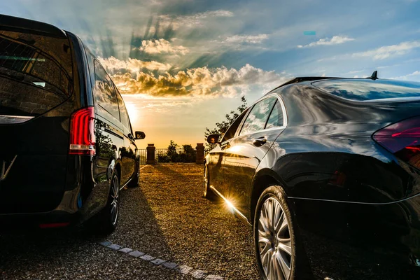 Dois carros de luxo voltados para o pôr do sol colorido, grande ângulo — Fotografia de Stock
