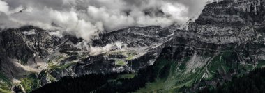 Korkunç cansız kayalar, Alpler 'de bir buzul, dağların zirvelerine yayılmış bulutlar ve sis. İsviçre