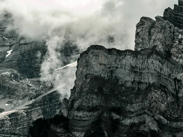 Terrible lifeless rocks, a glacier in the Alps, clouds and fog spread over the peaks of the mountains. Switzerland