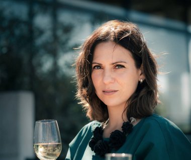 Restoranın açık terasında elinde bir bardak şarapla güzel bir genç kadın.